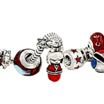 A close-up of a silver charm bracelet featuring various decorative charms, including a red and blue dragon bead, a red and white figure charm, a red chest charm, and a red box charm, all set against a plain white background.